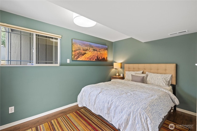 bedroom featuring visible vents, baseboards, and wood finished floors