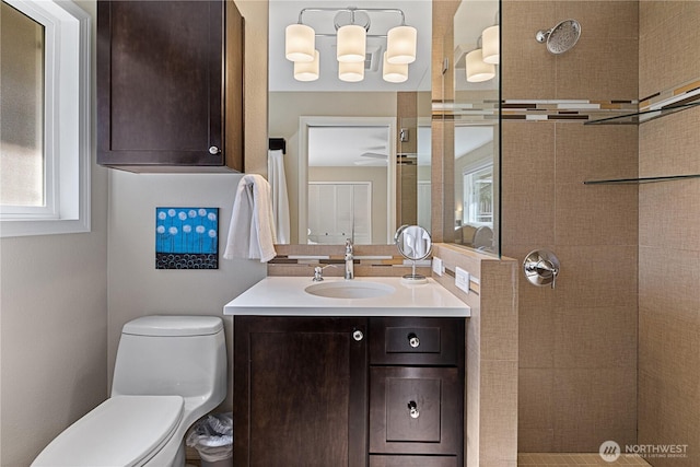 bathroom featuring toilet, vanity, and a tile shower