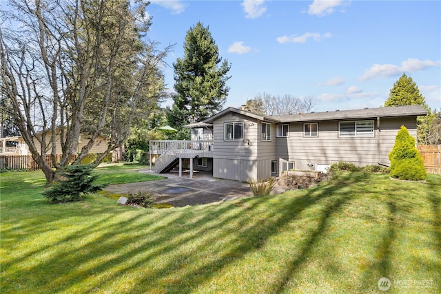 back of property with fence, a wooden deck, a yard, stairs, and a patio area