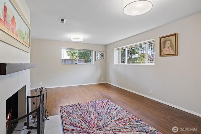 interior space with plenty of natural light, a tile fireplace, visible vents, and wood finished floors