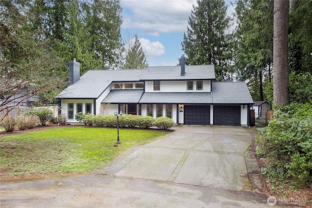 view of front of home featuring a front lawn, a chimney, a garage, and fence