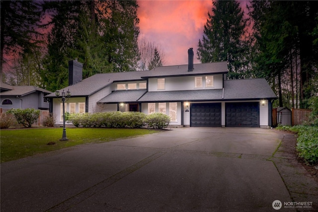 view of front of property featuring concrete driveway, a yard, a garage, and a chimney