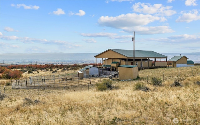 view of yard featuring an exterior structure, a mountain view, an outbuilding, and a rural view