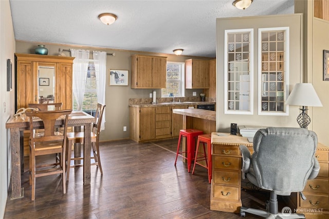 interior space with brown cabinetry, dark wood-style floors, light countertops, and a textured ceiling