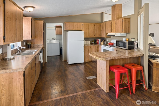 kitchen featuring ventilation hood, vaulted ceiling, washer / dryer, white appliances, and a sink