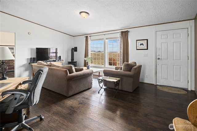 living room with wood-type flooring, a textured ceiling, ornamental molding, and a wood stove