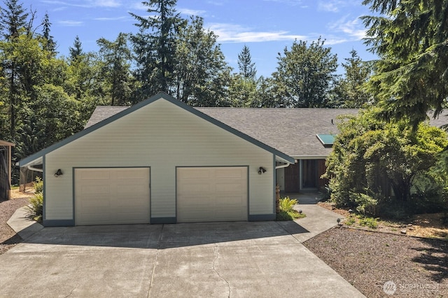 view of front facade with concrete driveway, an attached garage, and a shingled roof