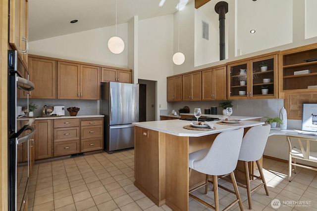 kitchen with visible vents, brown cabinets, light countertops, and freestanding refrigerator