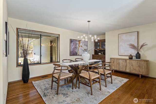 dining room featuring a notable chandelier, radiator, and wood finished floors