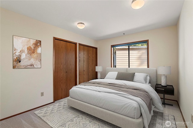 bedroom with multiple closets, baseboards, and light carpet