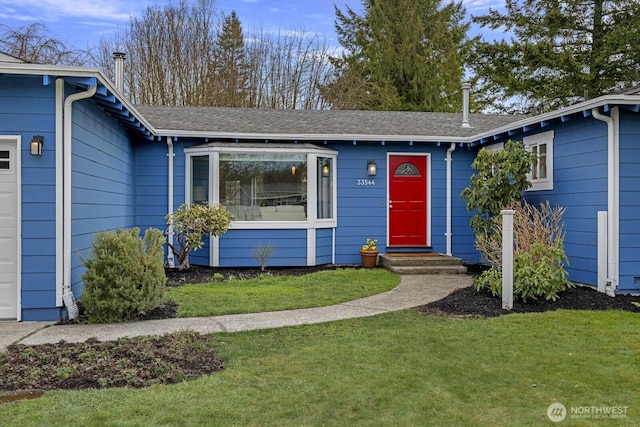 property entrance featuring a garage, a lawn, and a shingled roof