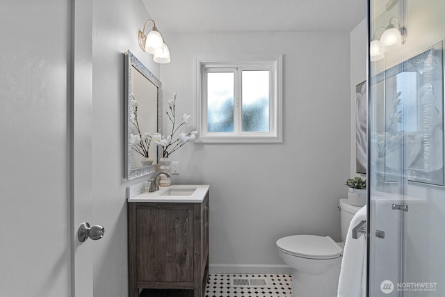 bathroom featuring visible vents, toilet, a stall shower, baseboards, and vanity