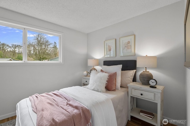 bedroom featuring a textured ceiling, baseboards, and wood finished floors