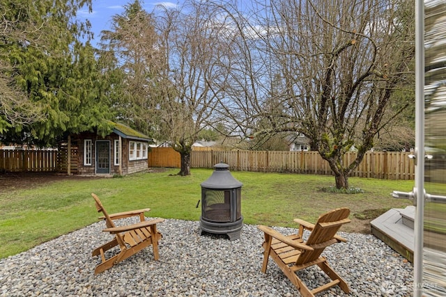 view of yard with an outdoor structure, a fenced backyard, and an outdoor fire pit