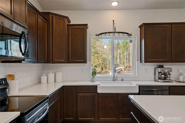 kitchen featuring appliances with stainless steel finishes, light countertops, a sink, and backsplash