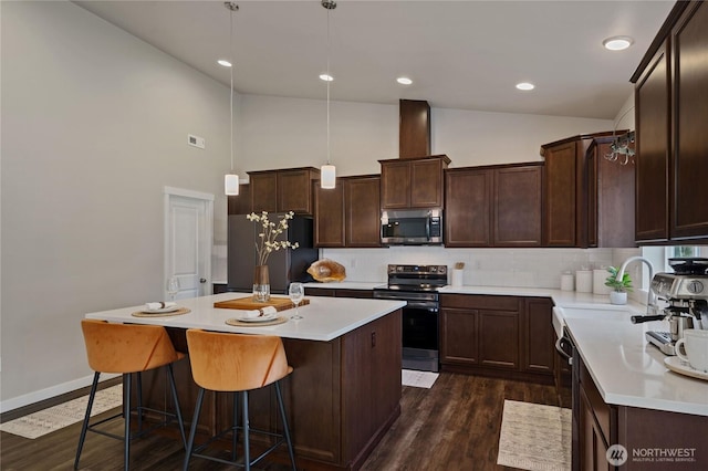 kitchen with dark brown cabinetry, a sink, appliances with stainless steel finishes, a center island, and dark wood-style floors