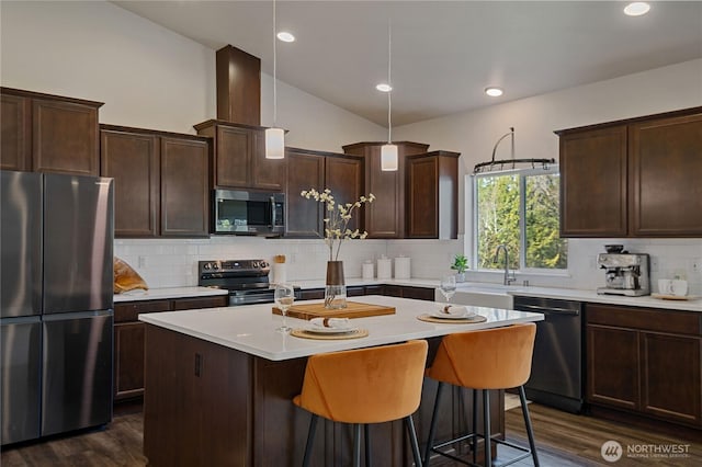 kitchen featuring dark brown cabinetry, appliances with stainless steel finishes, light countertops, and dark wood-type flooring