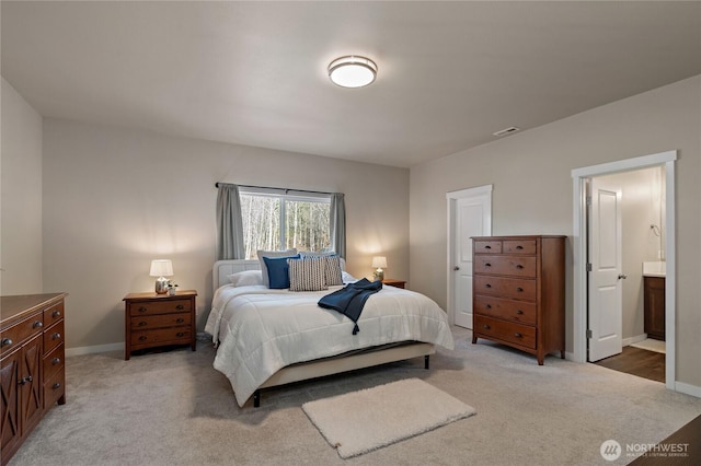 bedroom with baseboards, visible vents, connected bathroom, and light colored carpet