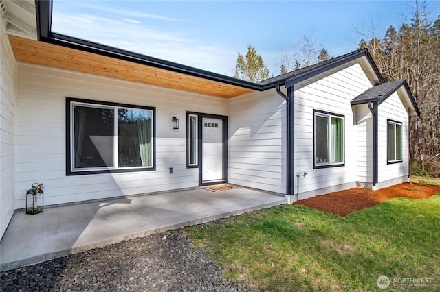 entrance to property with a patio area and a lawn