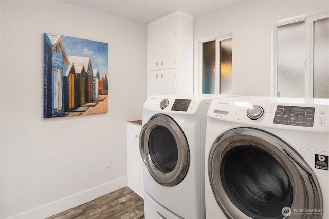 washroom featuring wood finished floors, cabinet space, washing machine and dryer, and baseboards