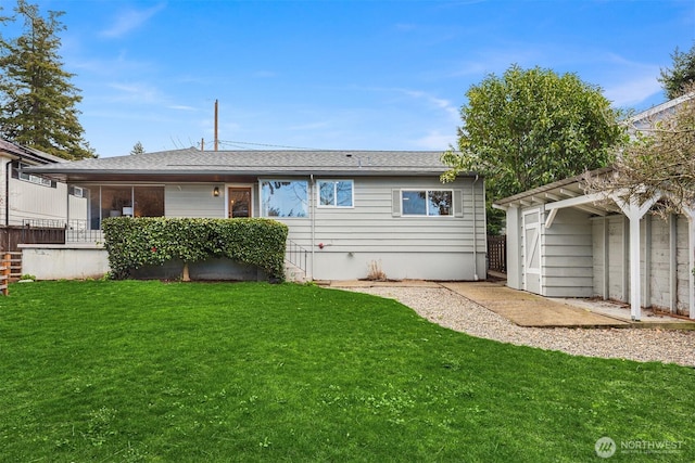 back of property with a yard and roof with shingles