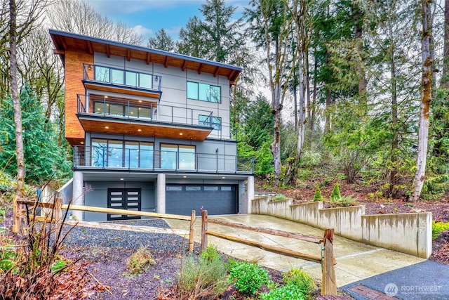 view of front of property featuring a fenced front yard, a balcony, an attached garage, and driveway