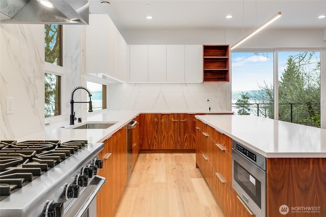 kitchen featuring light wood-style flooring, a sink, light countertops, modern cabinets, and brown cabinets