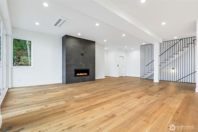 unfurnished living room featuring a tiled fireplace, visible vents, recessed lighting, and light wood-type flooring