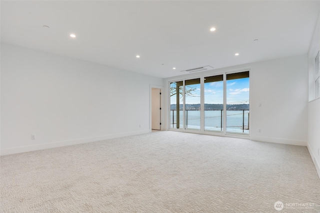 empty room featuring visible vents, floor to ceiling windows, recessed lighting, baseboards, and light colored carpet