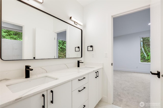 bathroom with a sink, baseboards, and double vanity