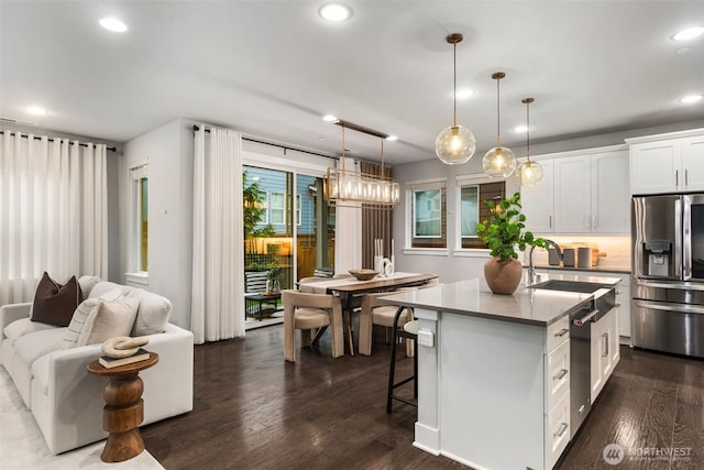 kitchen with dark wood-type flooring, an island with sink, recessed lighting, appliances with stainless steel finishes, and white cabinets