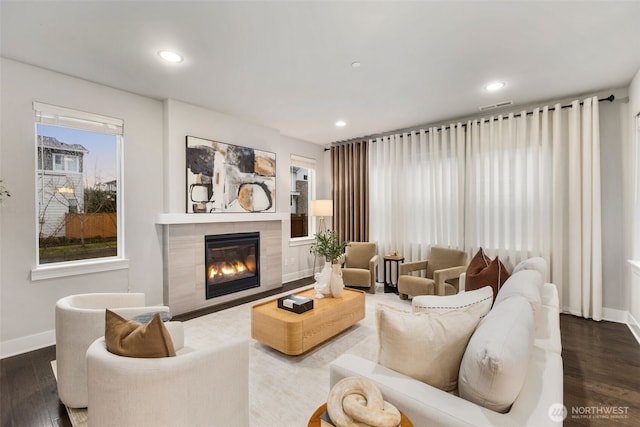 living room featuring a fireplace, wood finished floors, visible vents, and baseboards