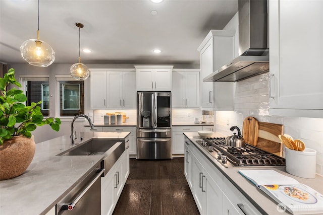 kitchen featuring a sink, stainless steel appliances, wall chimney exhaust hood, white cabinets, and dark wood-style flooring