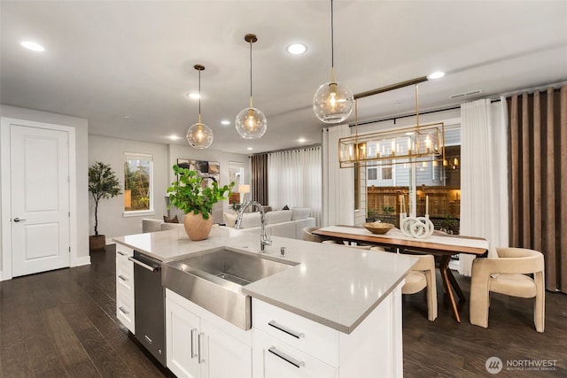 kitchen featuring dishwasher, hanging light fixtures, dark wood-style floors, white cabinets, and a sink