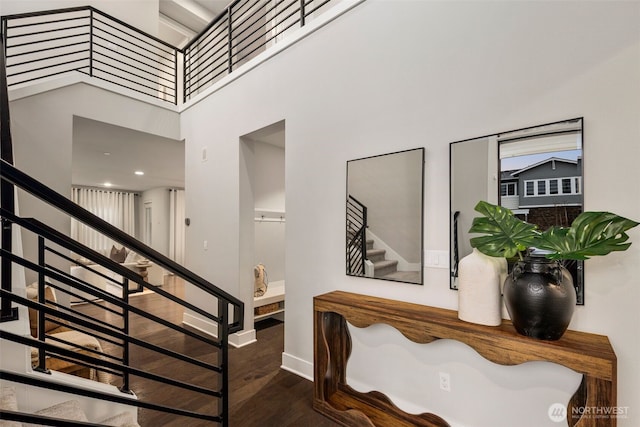 stairs featuring baseboards, wood finished floors, and a towering ceiling