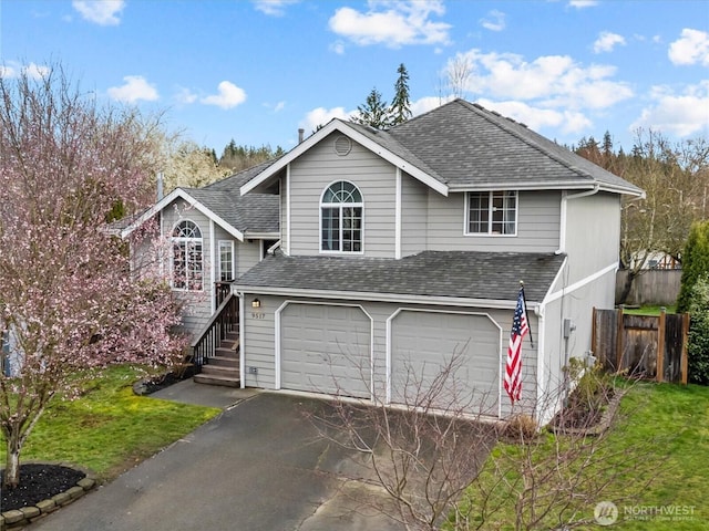 view of front facade featuring a garage, fence, driveway, and a shingled roof