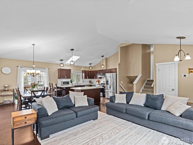 living room featuring lofted ceiling, stairway, dark wood-style flooring, and a chandelier