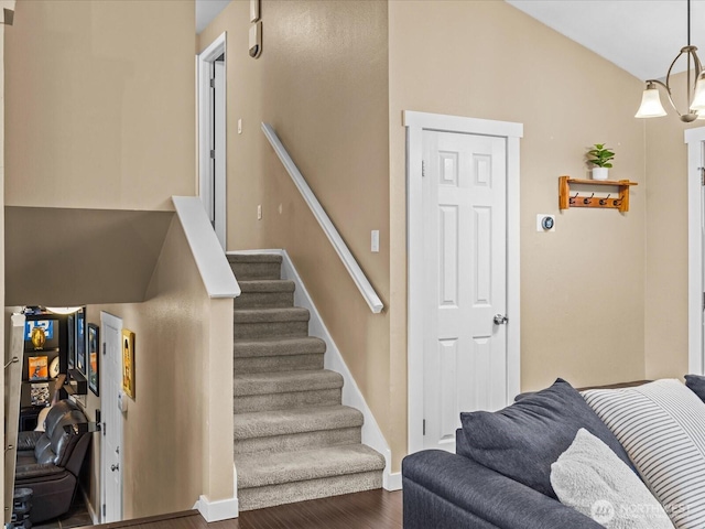 stairway with baseboards, wood finished floors, and vaulted ceiling