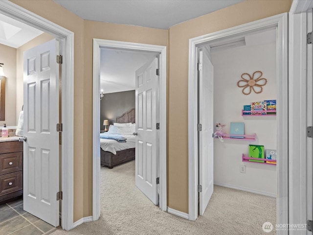 hallway featuring light colored carpet and baseboards