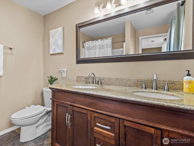 bathroom featuring double vanity, toilet, and a sink