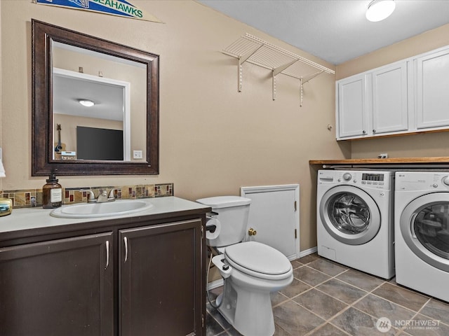 laundry room featuring a sink, dark tile patterned floors, laundry area, and washer and clothes dryer