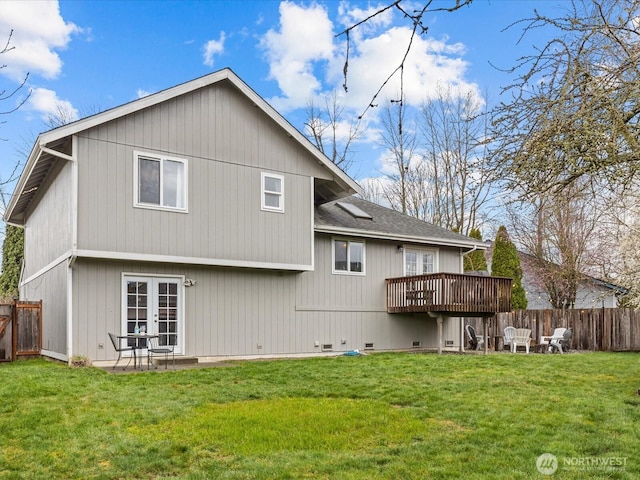 rear view of property featuring a lawn, fence, french doors, roof with shingles, and a wooden deck