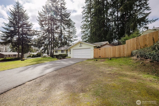 view of front of property with a front lawn, an attached garage, driveway, and fence