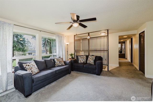 living area with carpet flooring, a textured ceiling, baseboards, and a ceiling fan