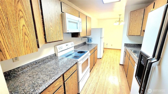 kitchen with baseboards, pendant lighting, light wood-style floors, a notable chandelier, and white appliances