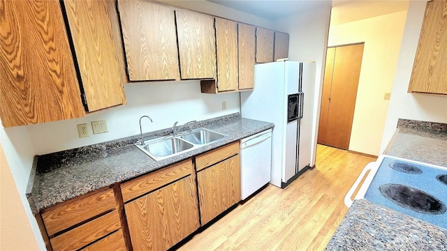 kitchen featuring a sink, white appliances, light wood-style floors, and dark countertops