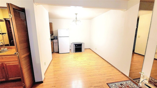 interior space with a notable chandelier, light wood-style floors, and a sink