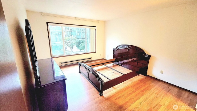 bedroom featuring a baseboard heating unit and wood finished floors