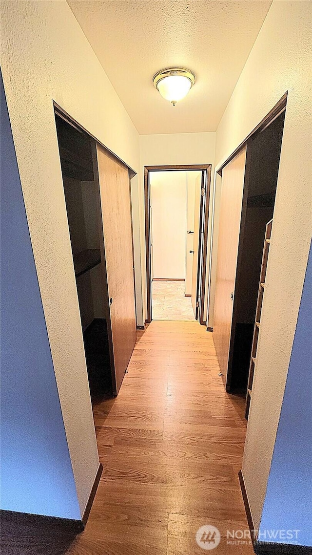 corridor featuring a textured ceiling and wood finished floors