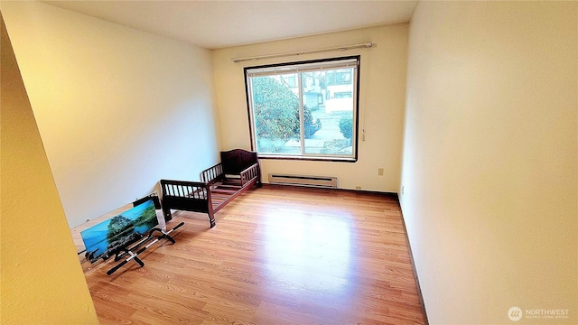 interior space featuring a baseboard heating unit and wood finished floors